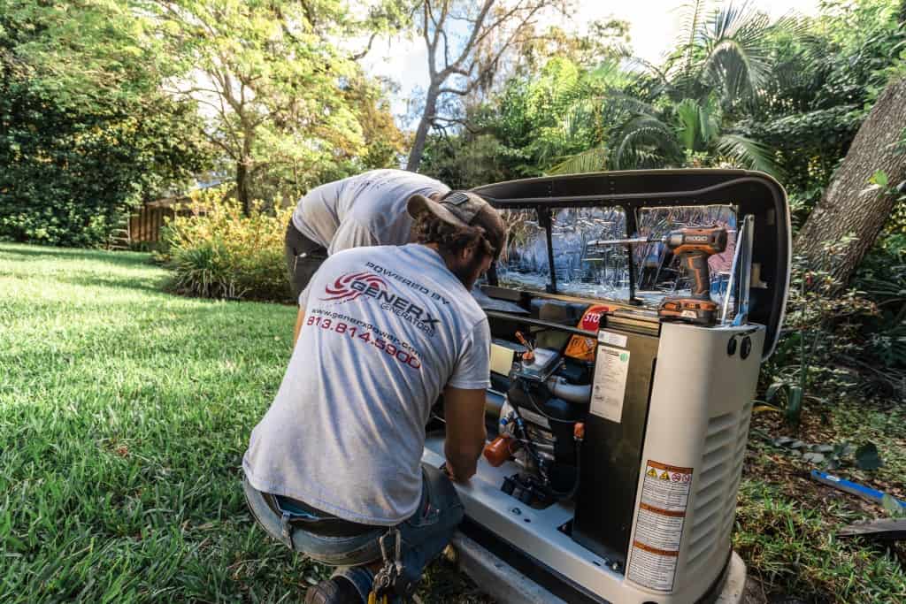 GenerX technician servicing an installed Generac generator in a backyard